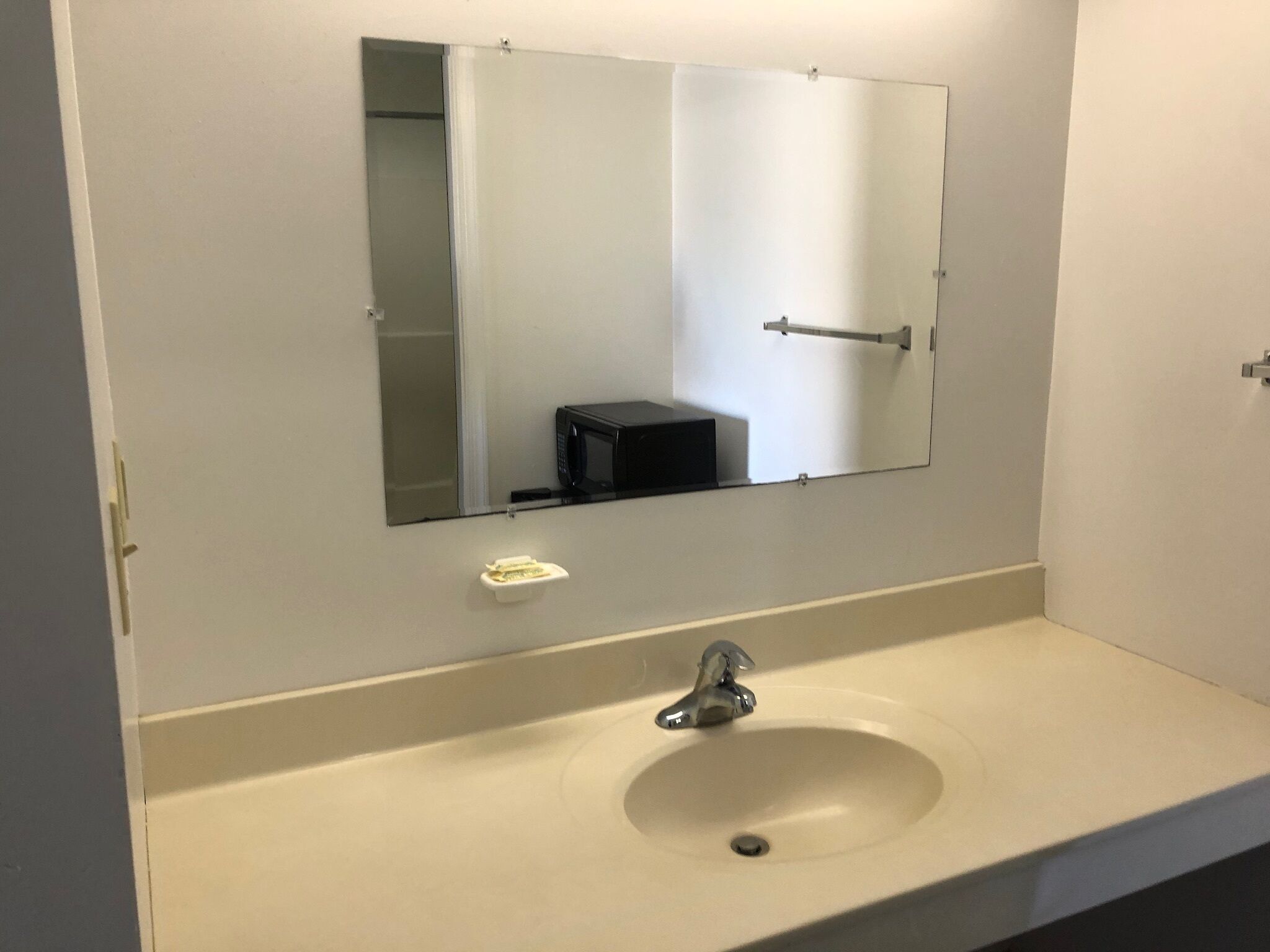 A bathroom with a sink, mirror, and a small trash bin.