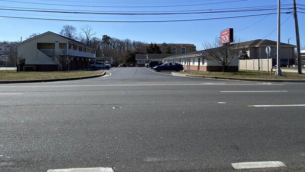Vista de la calle con un letrero de motel, un edificio con el número 1760 y coches estacionados.