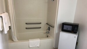 Un baño con bañera, inodoro y microondas.