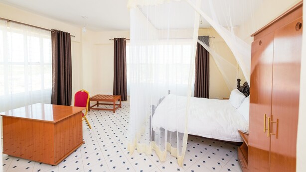 Ein Hotelzimmer mit einem Bett, einem Holztisch, einem Stuhl und einem Kleiderschrank.