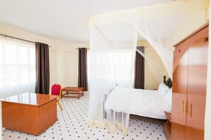 A hotel room with a bed, a wooden desk, a chair, and a wardrobe. - Shuhan Hotel Kabati (Kabati)