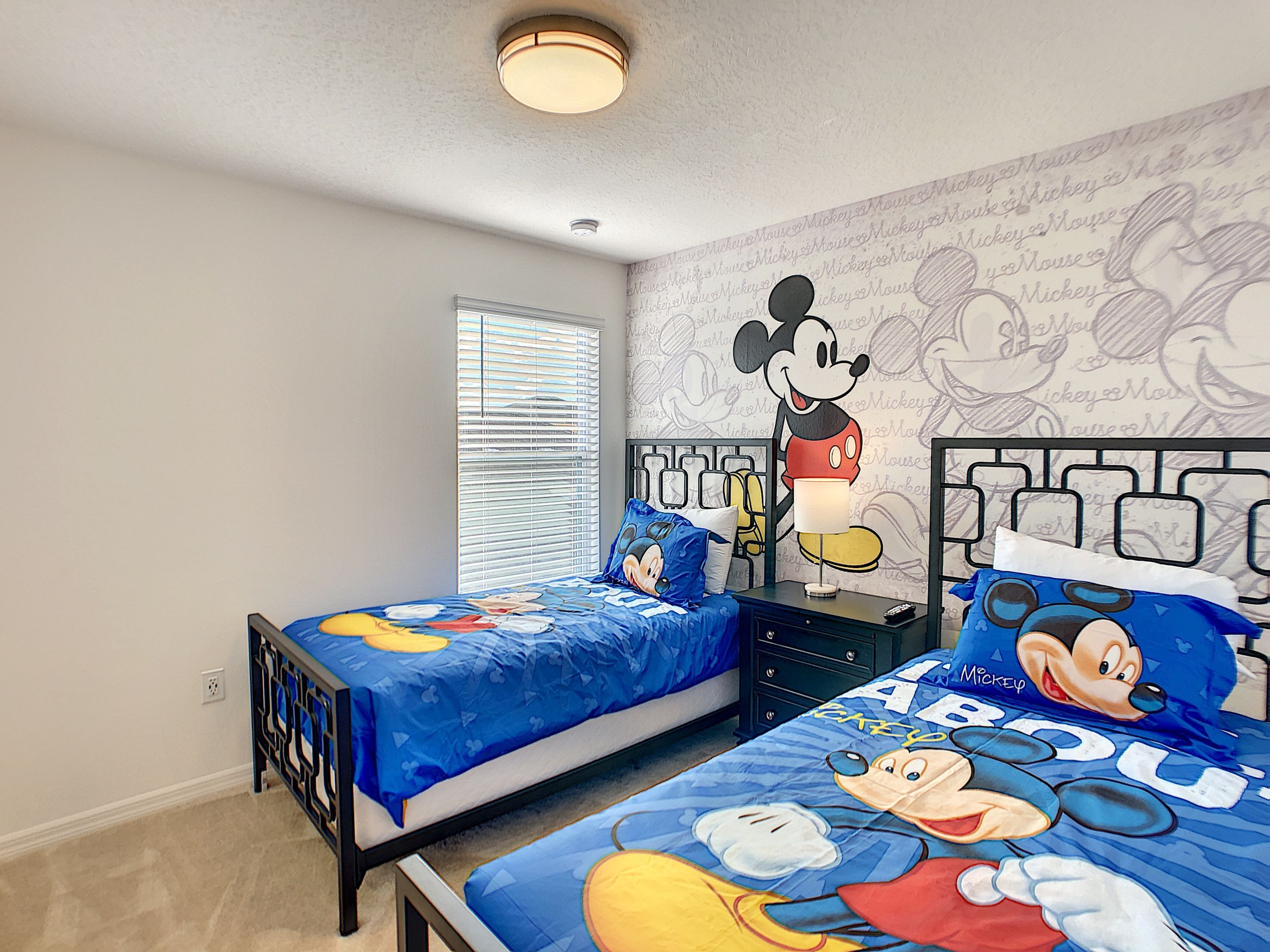Et soveværelse med to senge, hver med Mickey Mouse sengetøj.