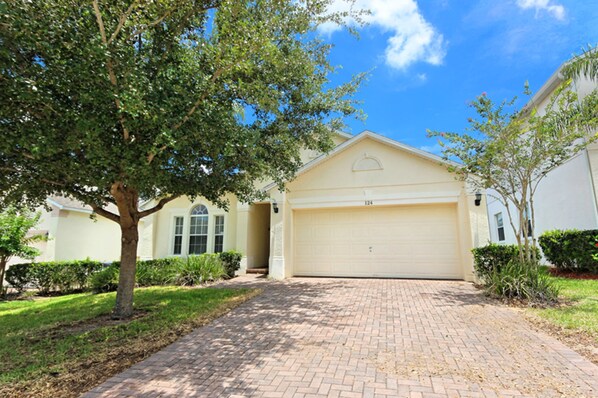 A residential house with a garage, a driveway, and a tree in the front yard.