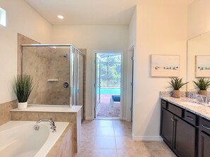 A modern bathroom with a walk-in shower, a large bathtub, and a countertop with a sink and plants.