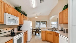 Una cocina con gabinetes de madera, microondas, estufa y refrigerador.