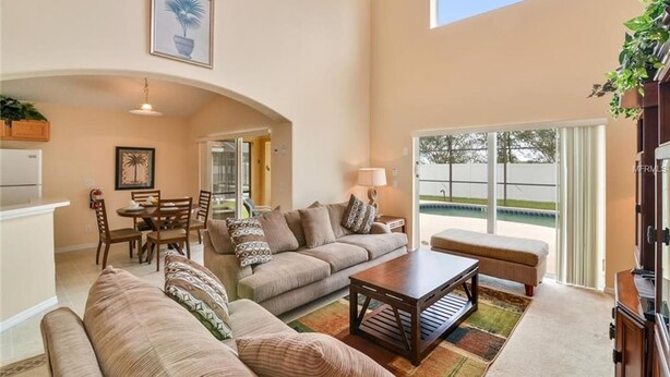 Un salón comedor amplio con techo alto y vista a una piscina.