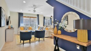 A modern living room with a sofa, two chairs, a coffee table, and a dining area with a wooden table and chairs. - Lotus Garden by Florida Spirit (Kissimmee)