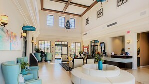 A spacious lobby with a central seating area, a reception desk, and artwork on the walls. - Lotus Garden by Florida Spirit (Kissimmee)