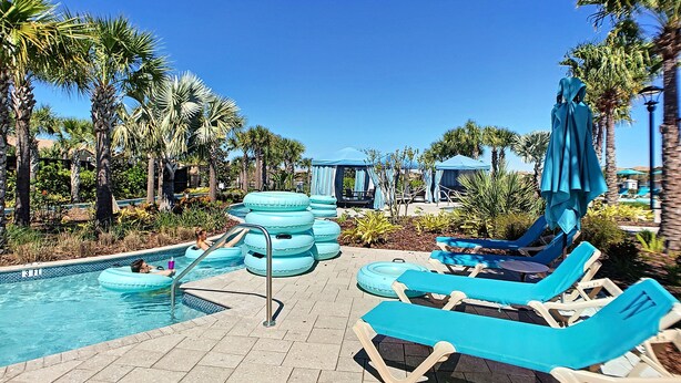 A pool area with lounge chairs, a water slide, and palm trees. - Lotus Garden by Florida Spirit (Kissimmee)