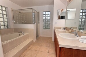 A modern bathroom with a large bathtub, two sinks, and a large mirror.