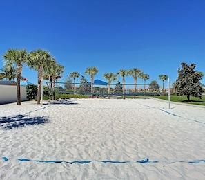 Enjoy a game of volleyball on the sandy court surrounded by palm trees and a scenic view.