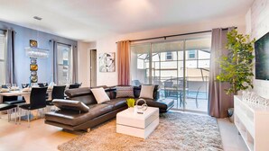 A modern living room with a sofa, coffee table, and dining area. - Tropical Sunset by Florida Spirit (Kissimmee)