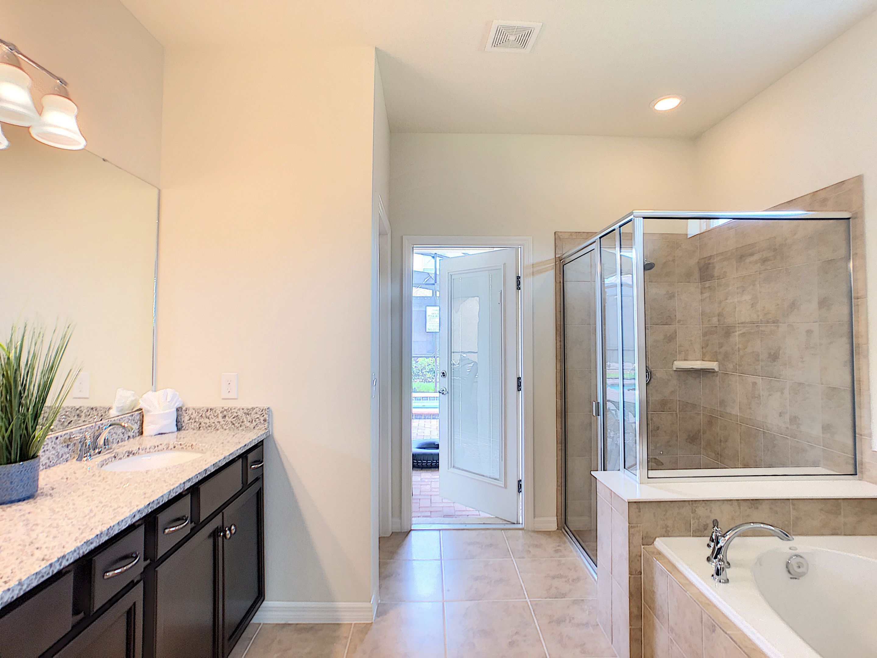 A modern bathroom with a large mirror, a walk-in shower, and a bathtub.