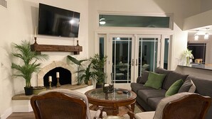 A living room with a fireplace, a television, and a dining area with chairs and a table. - 9 AM check in 9 PM check out, south facing sunny yard, Kierland area, 6 bikes (Scottsdale)