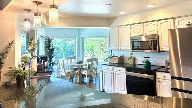 A modern kitchen with white cabinets, stainless steel appliances, and a glass island. - 9 AM check in 9 PM check out, south facing sunny yard, Kierland area, 6 bikes (Scottsdale)