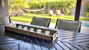 An outdoor seating area with a table and chairs, a hammock, and a view of a pool and garden. - 9 AM check in 9 PM check out, south facing sunny yard, Kierland area, 6 bikes (Scottsdale)