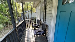 Eine Veranda mit blauer Tür, schwarzem Geländer und zwei Stühlen.
