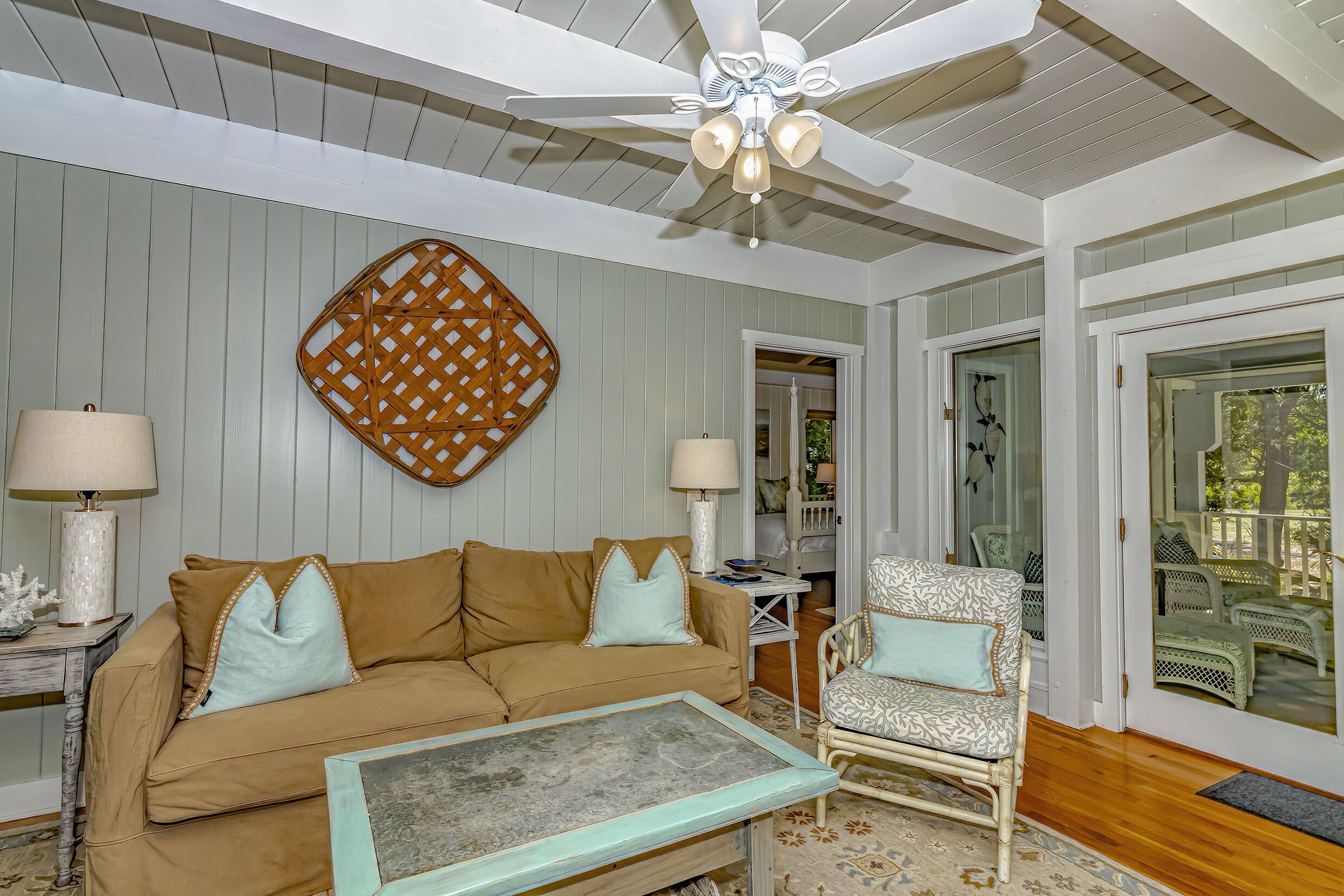 A cozy living room with a beige sofa, patterned armchair, and a ceiling fan.