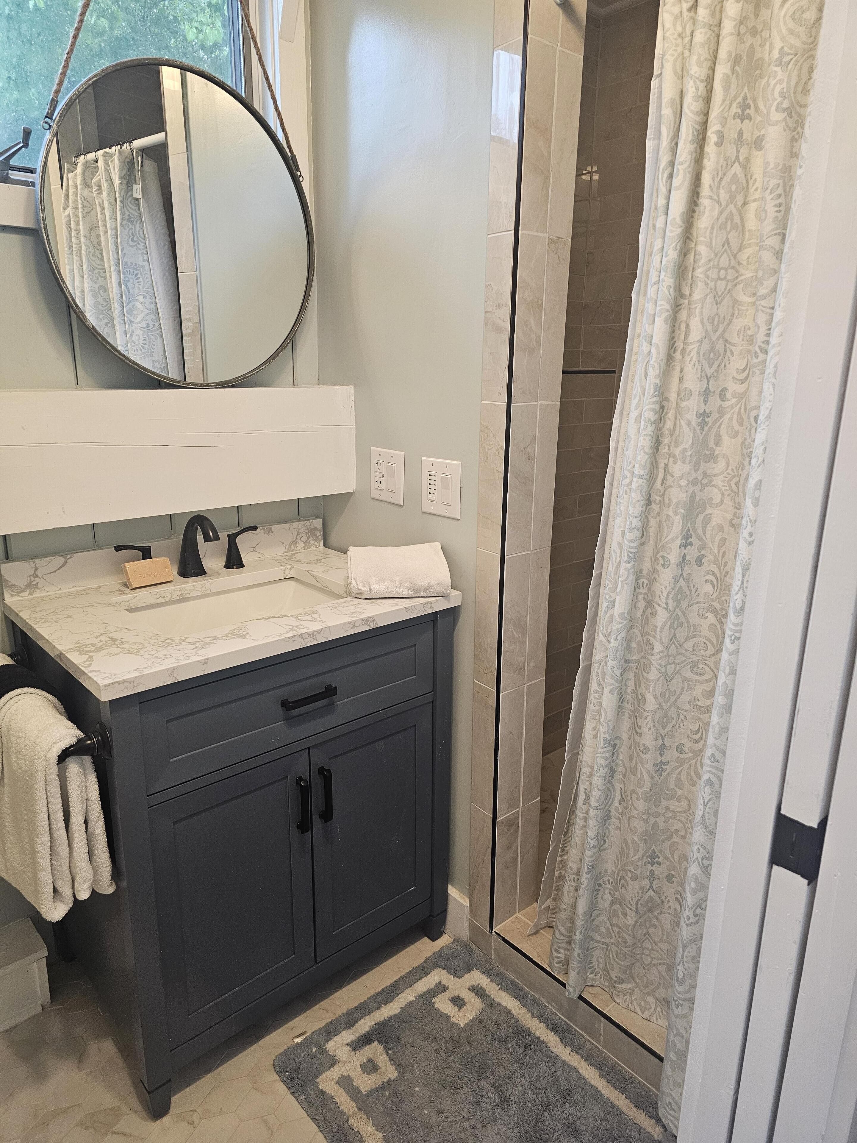 A bathroom with a dark vanity, a mirror, a towel, and a shower curtain.
