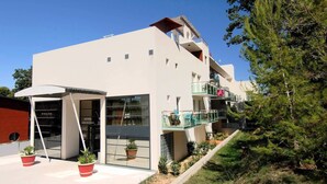 Ein modernes, zweistöckiges Gebäude mit flachem Dach, großen Fenstern und einem Balkon mit Glasgeländern.