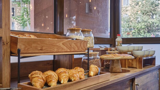 Un buffet per la colazione con croissant, granola e caffè.