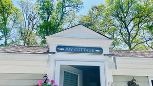 Una casa con un cartel que dice "JOY COTTAGE" sobre la entrada.