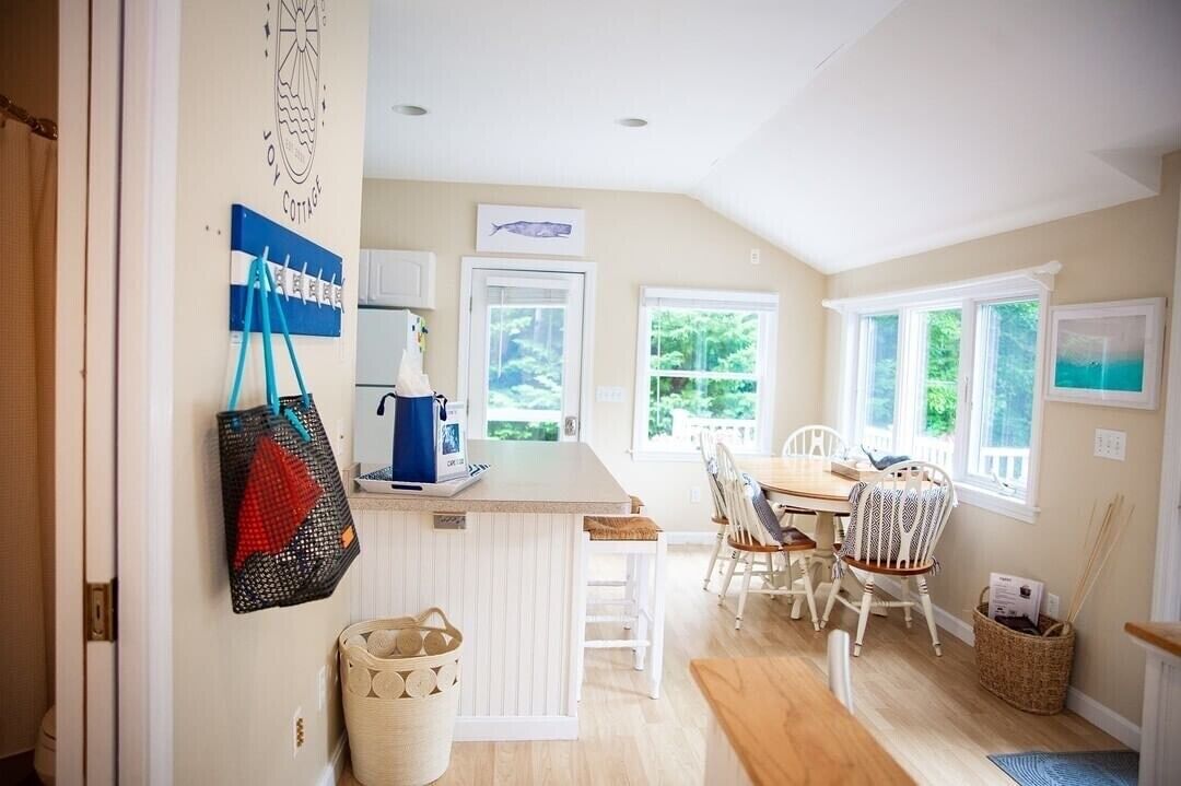 A cozy kitchen with a dining area, wooden flooring, and large windows.
