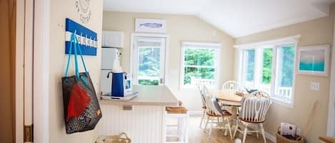 A cozy kitchen with a dining area, wooden flooring, and large windows.