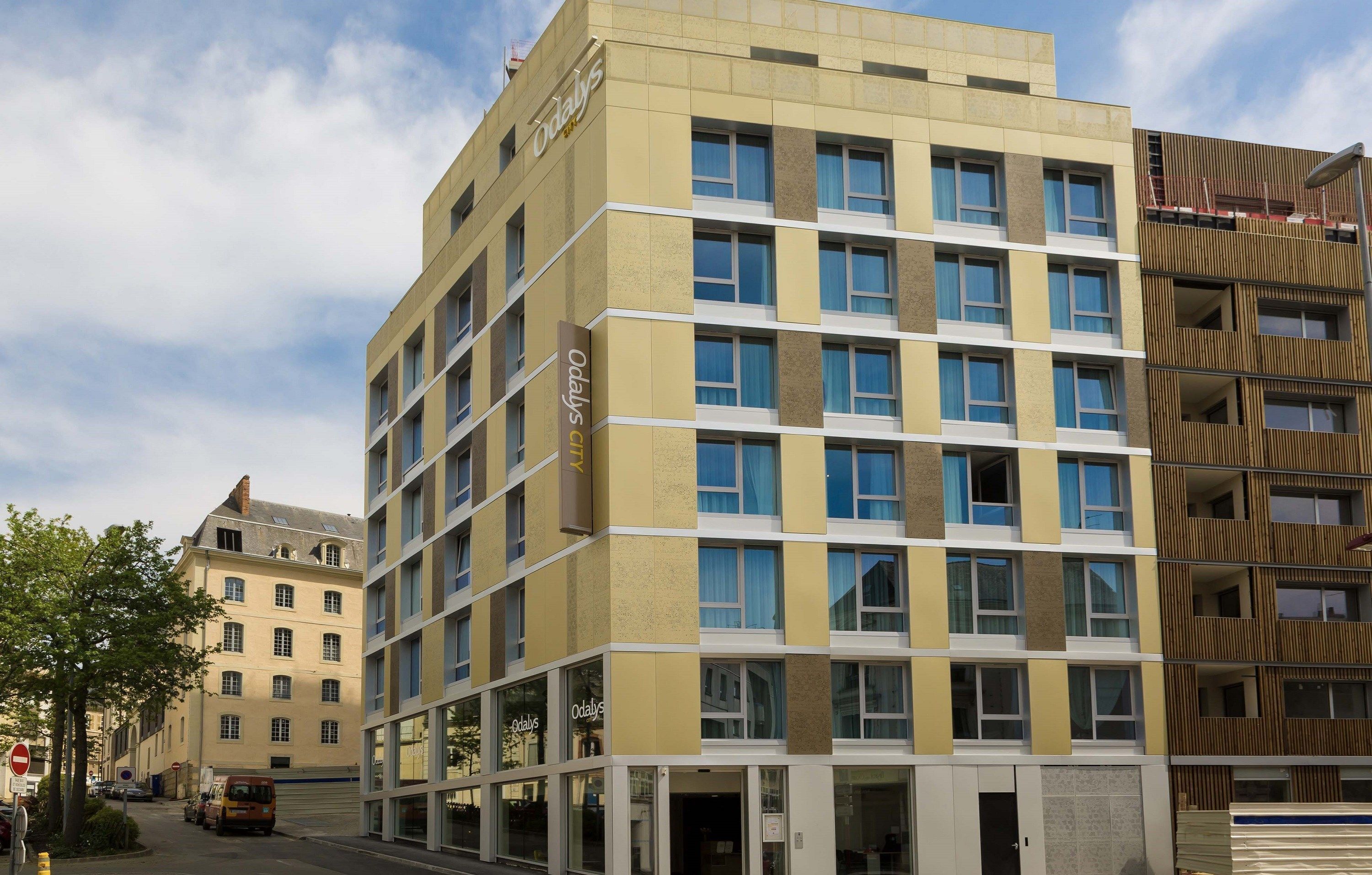 A multi-story hotel with a modern design, featuring a mix of window styles and a prominent 'Odaly's' sign on the facade.
