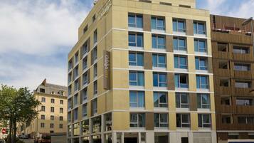 A multi-story hotel with a modern design, featuring a mix of window styles and a prominent 'Odaly's' sign on the facade.