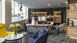 A modern lounge area with a sofa, armchairs, a coffee table, and a bookshelf. - Studio Proche de la Sarthe, Accès Hammam (Le Mans)