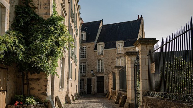A cobblestone street in a historic town with stone buildings, a wrought iron fence, and a clear sky. - Studio Proche de la Sarthe, Accès Hammam (Le Mans)
