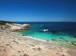 A rocky coastline with clear turquoise waters and a boat anchored near the shore.