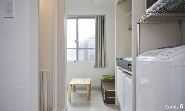 A laundry room with a washing machine, a drying rack, and a small wooden bench.