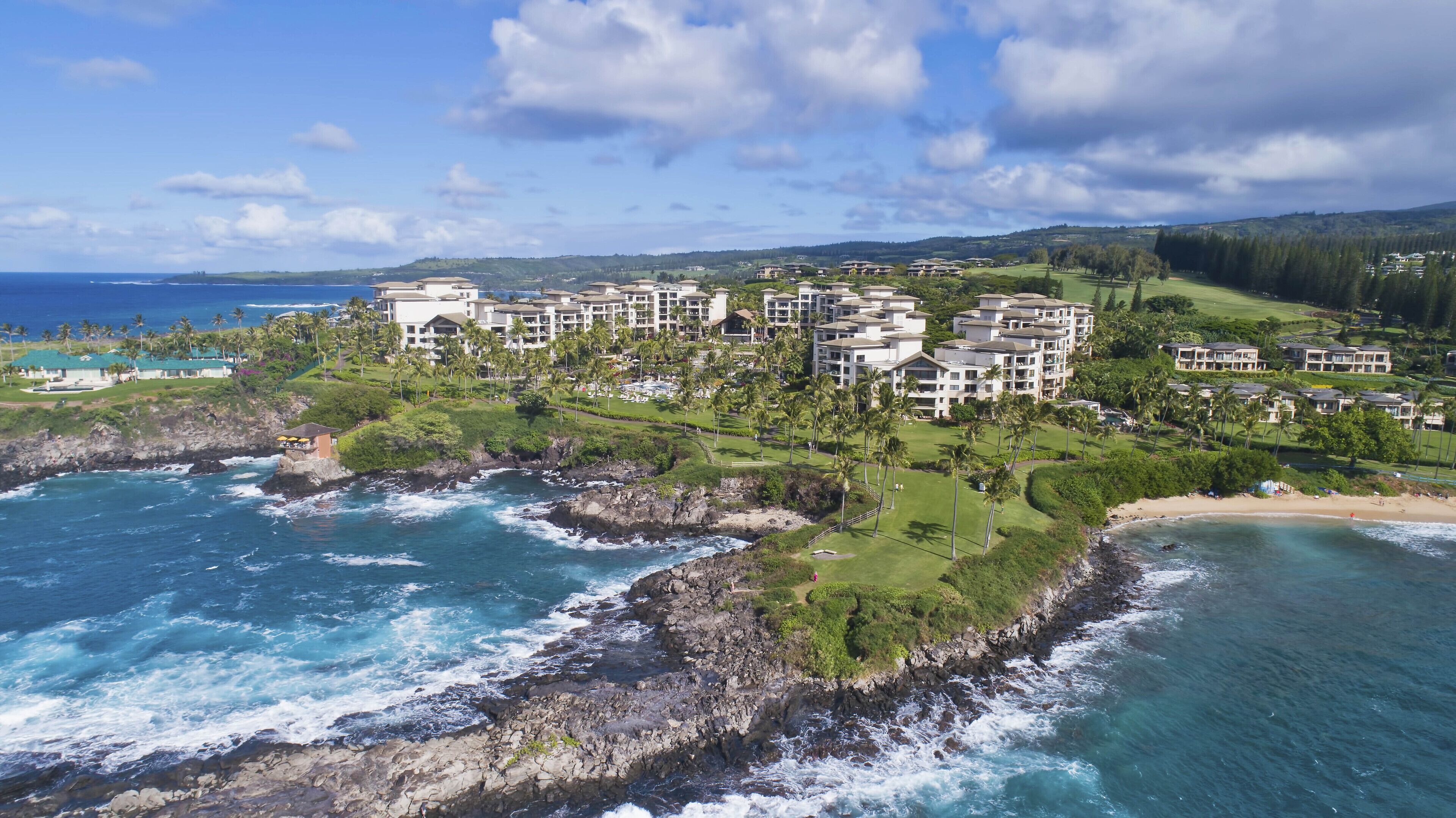 A coastal resort with multiple buildings, a rocky shoreline, and a view of the ocean.