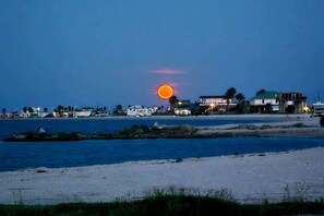 A beach scene with a sunset, buildings, and a boat. - SUNRISE ON MAG - Beach House (Port Lavaca)