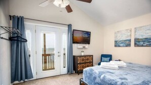 A bedroom with a bed, a television, a dresser, and a balcony door. - SUNRISE ON MAG - Beach House (Port Lavaca)