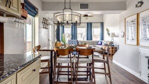 A kitchen with a central island, wooden chairs, a dining table, and a ceiling fan. - SUNRISE ON MAG - Beach House (Port Lavaca)