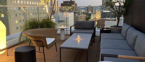 Une terrasse sur le toit, aménagée avec des meubles en osier, une table ronde et un canapé.