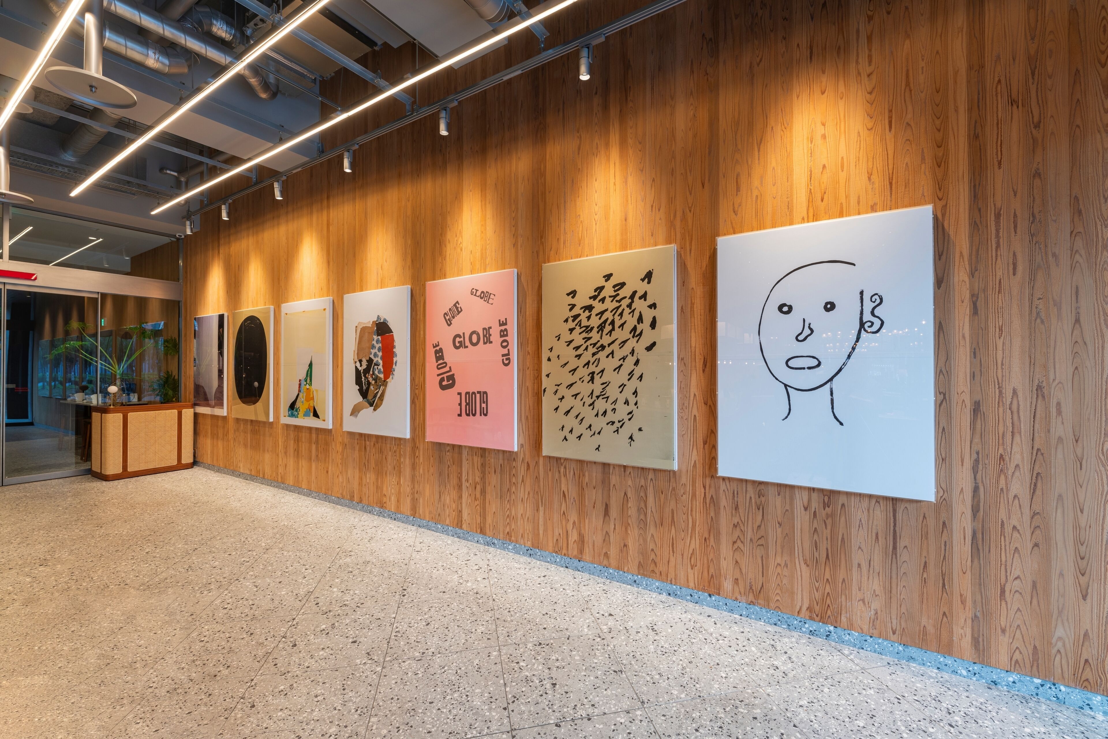 A hallway with wooden paneling and a series of framed artworks on the wall.