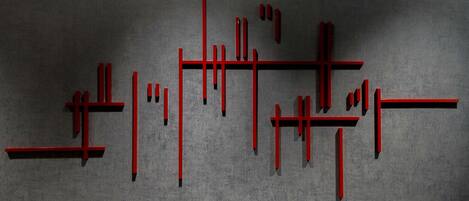 A geometric pattern of red lines on a textured grey background.