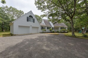 Propiedad residencial con camino de grava, casas blancas y un gran árbol.