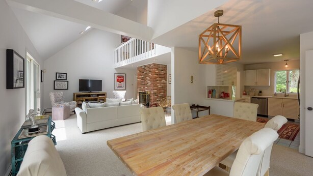 A spacious living area with a high ceiling, a dining table, and a kitchen area.