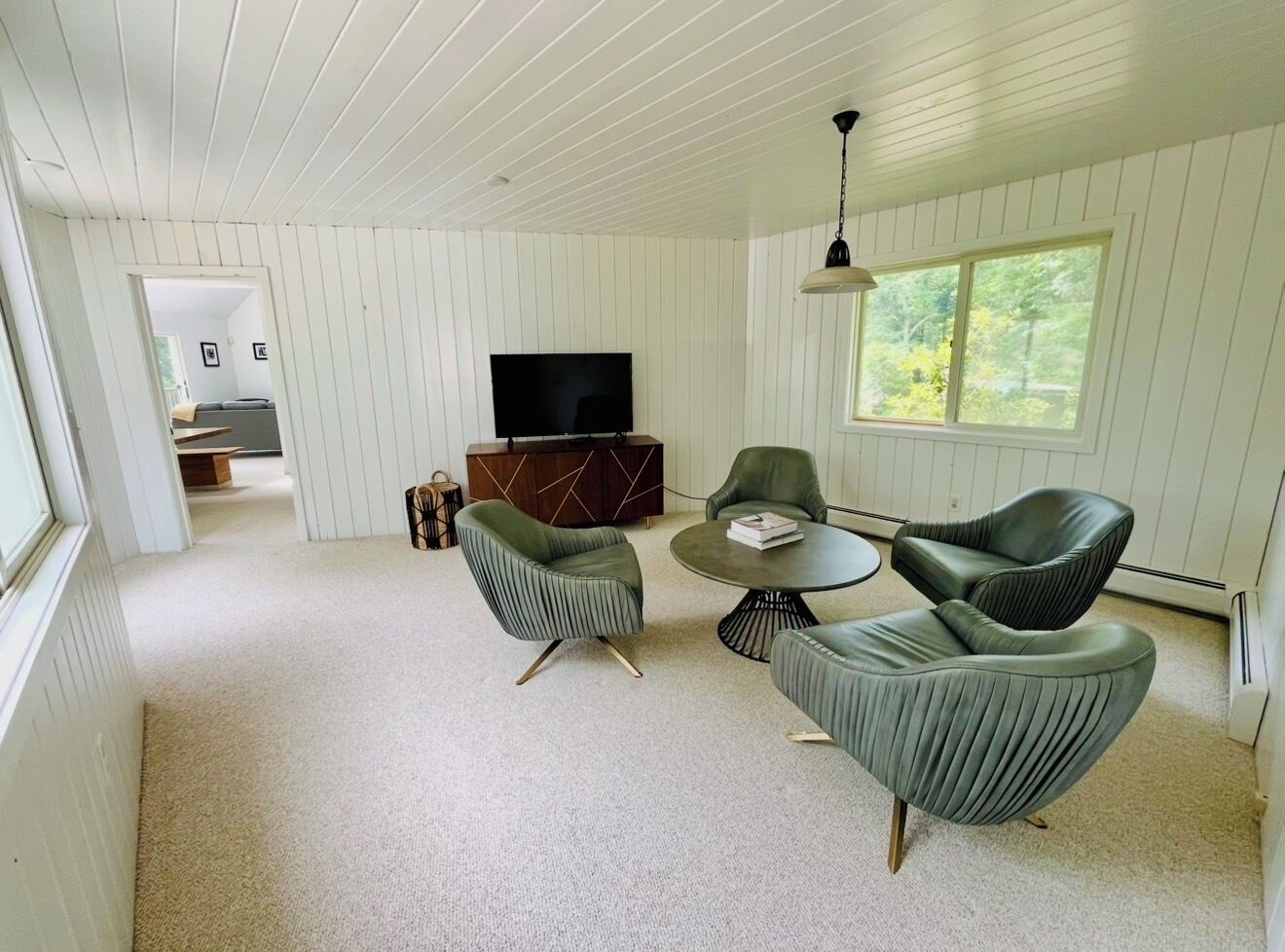 A room with a television, a dining table, and two chairs.