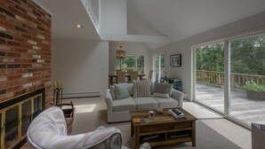A spacious living room with a brick fireplace, a large window, and a wooden coffee table.