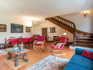 A spacious living room with a dining area, a staircase, and a blue sofa.