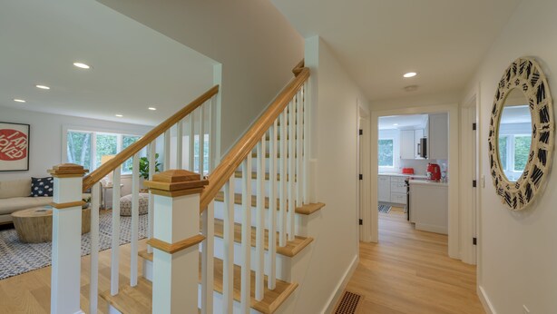 Un intérieur moderne avec un escalier en bois, un coin cuisine et un espace de vie comprenant un canapé et une table basse.