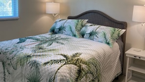 Een slaapkamer met een bed, twee bedlampen, een plafondventilator en een raam met zonwering.