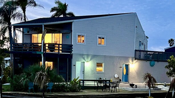 Een huis met twee verdiepingen, een balkon, een zwembad en een deur met een blauwe deurbel.