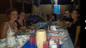 Un grupo de personas cenando en una mesa con diferentes platos, vasos y una jarra.